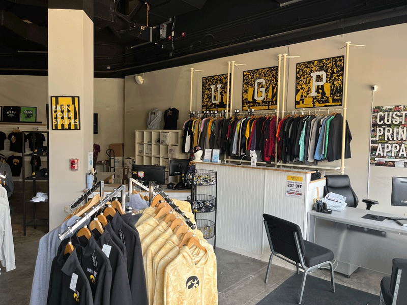 The interior of a well-stocked custom apparel store featuring racks of blank and printed garments, representing the ideal local airbrush t shirt shop to visit when you want to Airbrush a T-Shirt and design custom airbrush clothing little rock.
