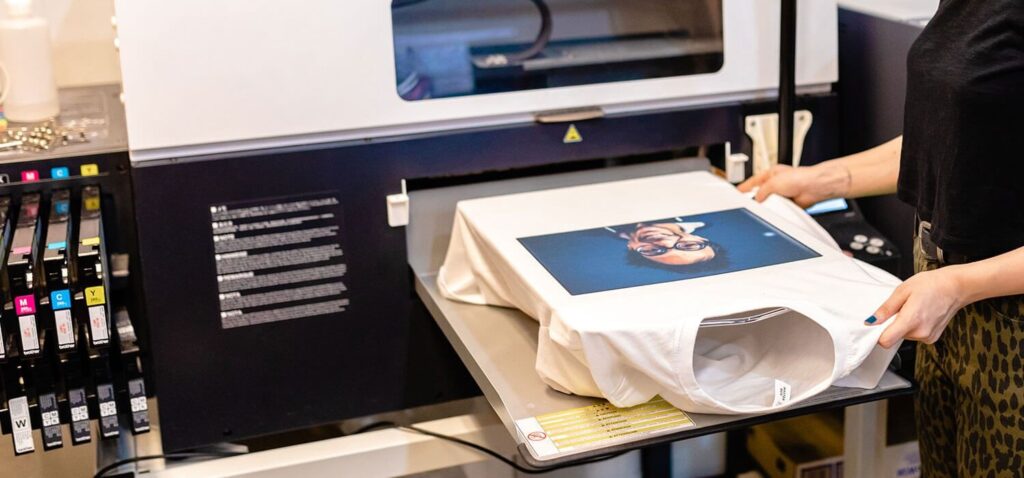 Little Rock Print Shop worker using DTG printer to create custom shirts with detailed full-color design.T-Shirt Printing in Little Rock