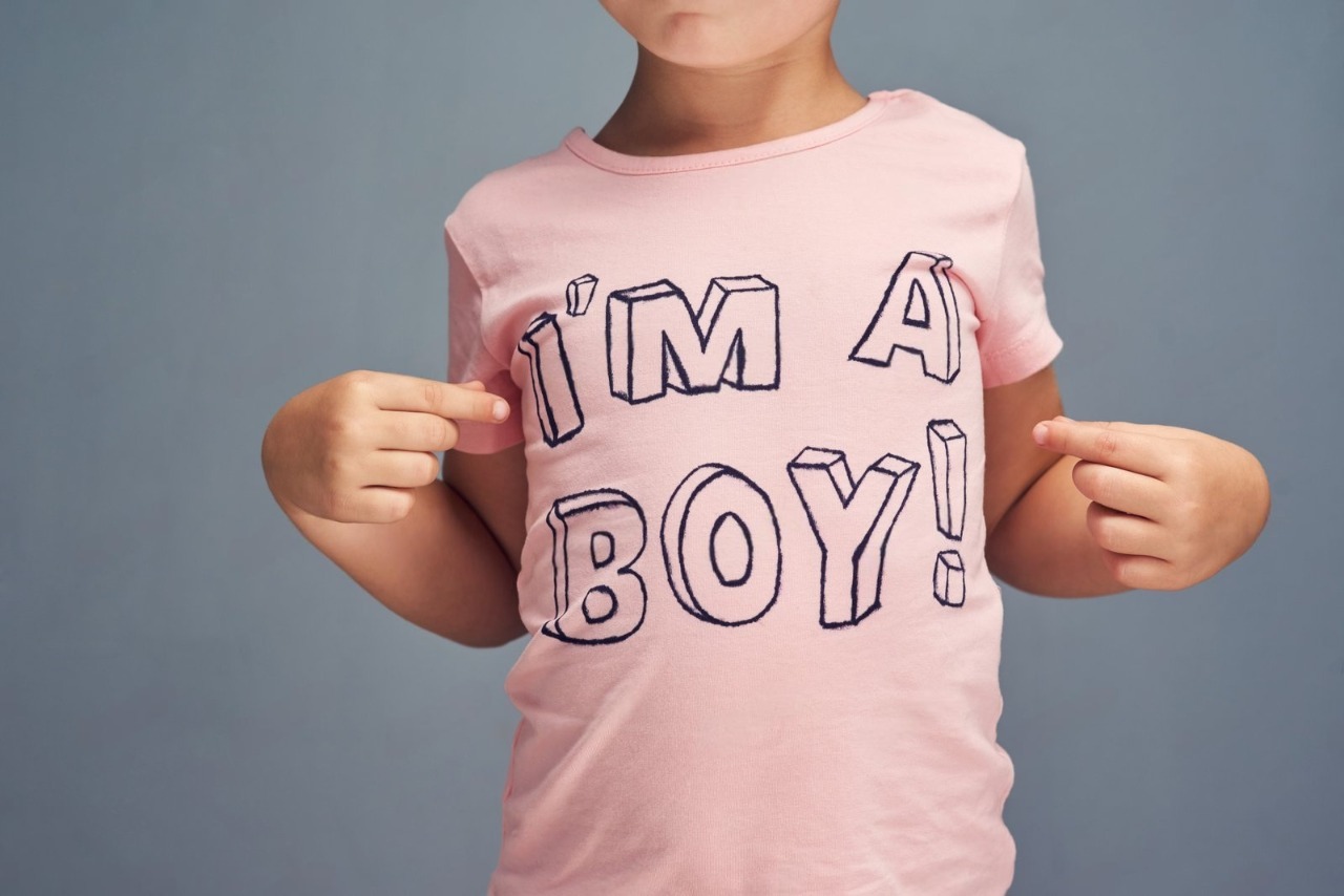 A close-up of a young boy proudly pointing to his pink custom t-shirt reading "I'M A BOY!", showcasing the fun, high-quality results of Boy's Affordable T-Shirt Printing for parents seeking cheap t shirts printing and durable affordable custom t shirts.