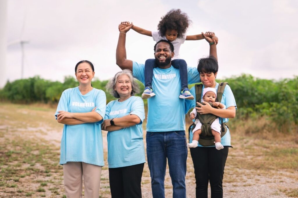 A happy, multi-generational family smiling together outdoors while wearing matching light blue custom t-shirts, showcasing the perfect inspiration for families looking to order family reunion shirts near me or custom family reunion shirts little rock apparel.Create unforgettable memories and capture the perfect group photo with the best family reunion shirts near me! Finding the right custom family reunion shirts near me makes it easy to bring everyone closer together, from the toddlers to the grandparents